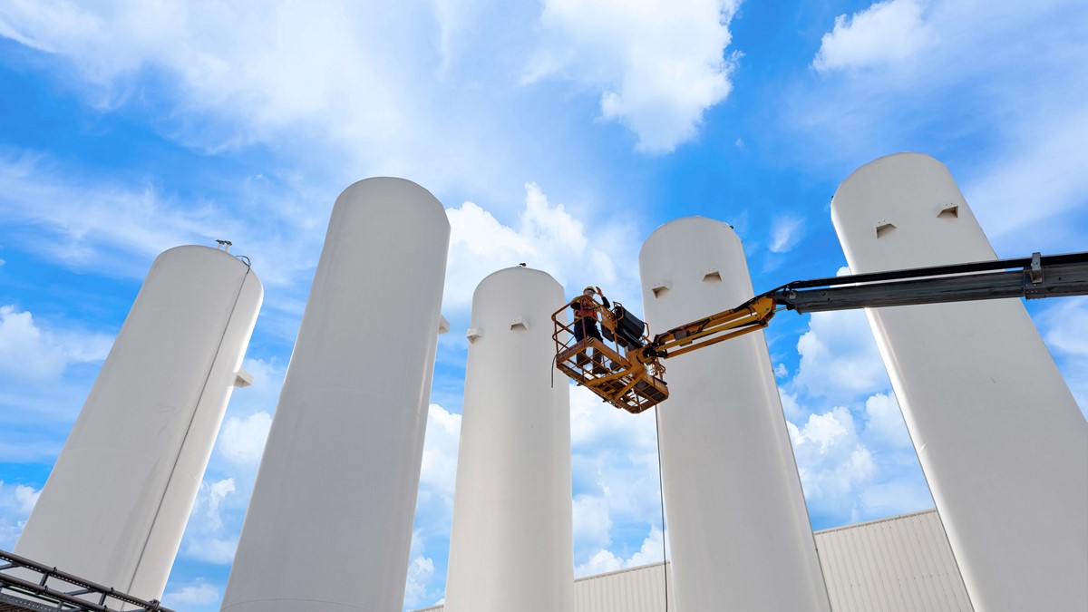 Five white recovery separator towers with an operator on a platform 