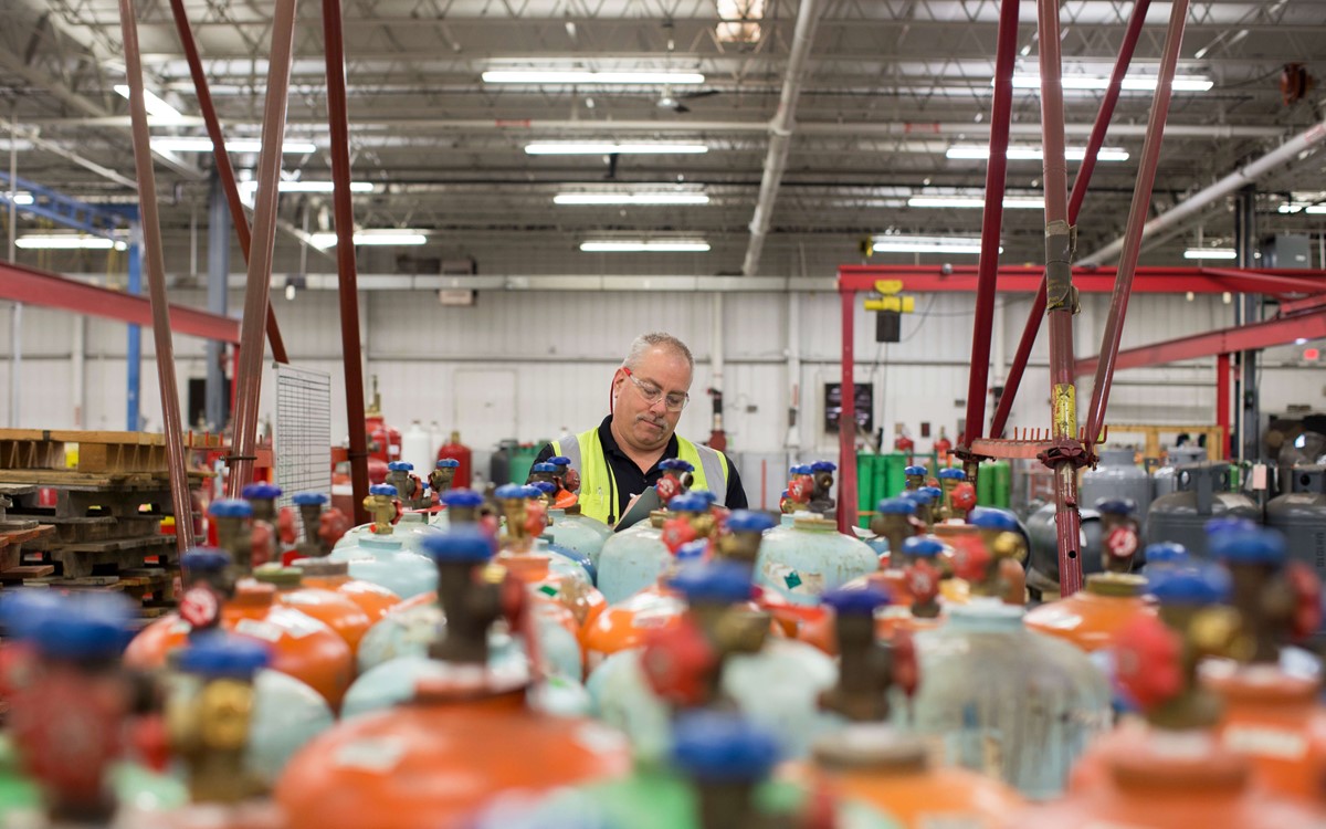 A warehouse worker stood behind rows of gas cylinders