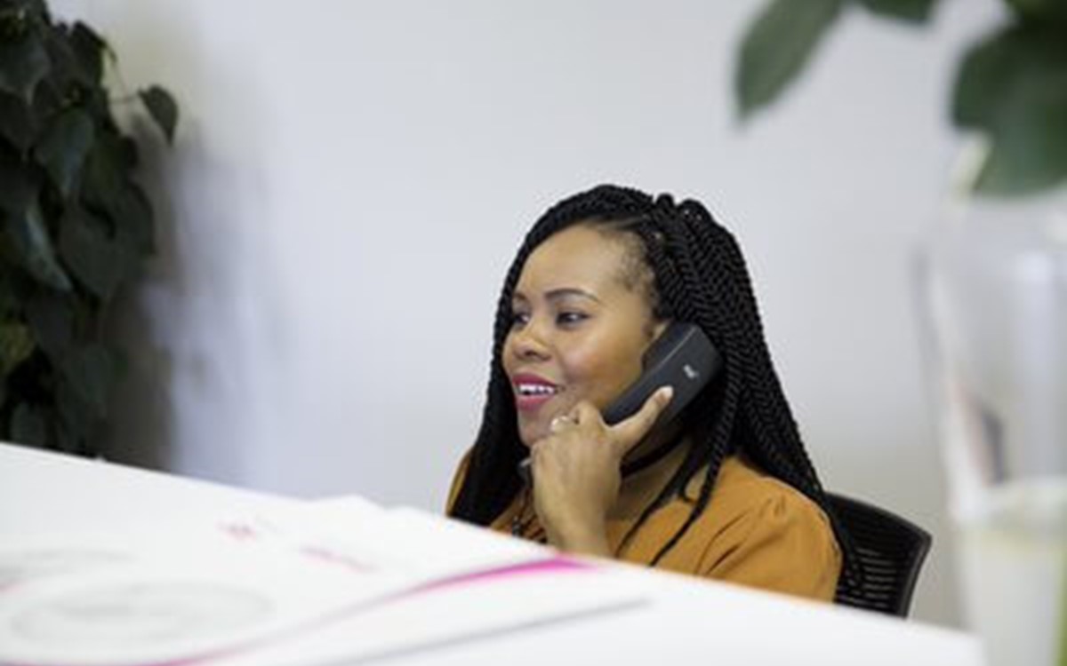 A woman sat at a desk using the phone