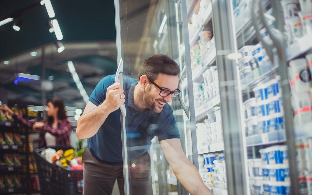 man in supermarket shopping for goods from chiller cabinet