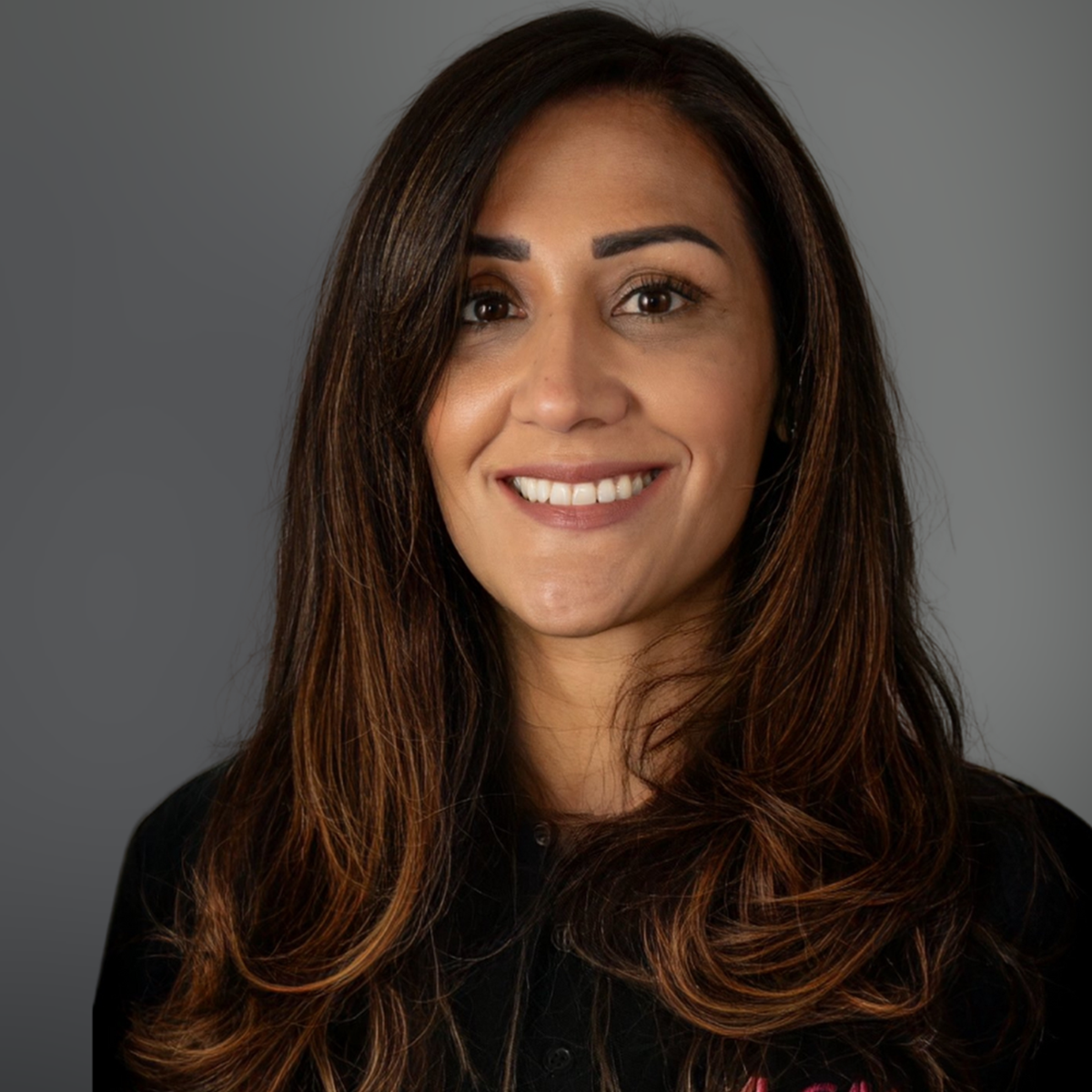 A woman in a black top with the pink A-Gas logo smiles at the camera 
