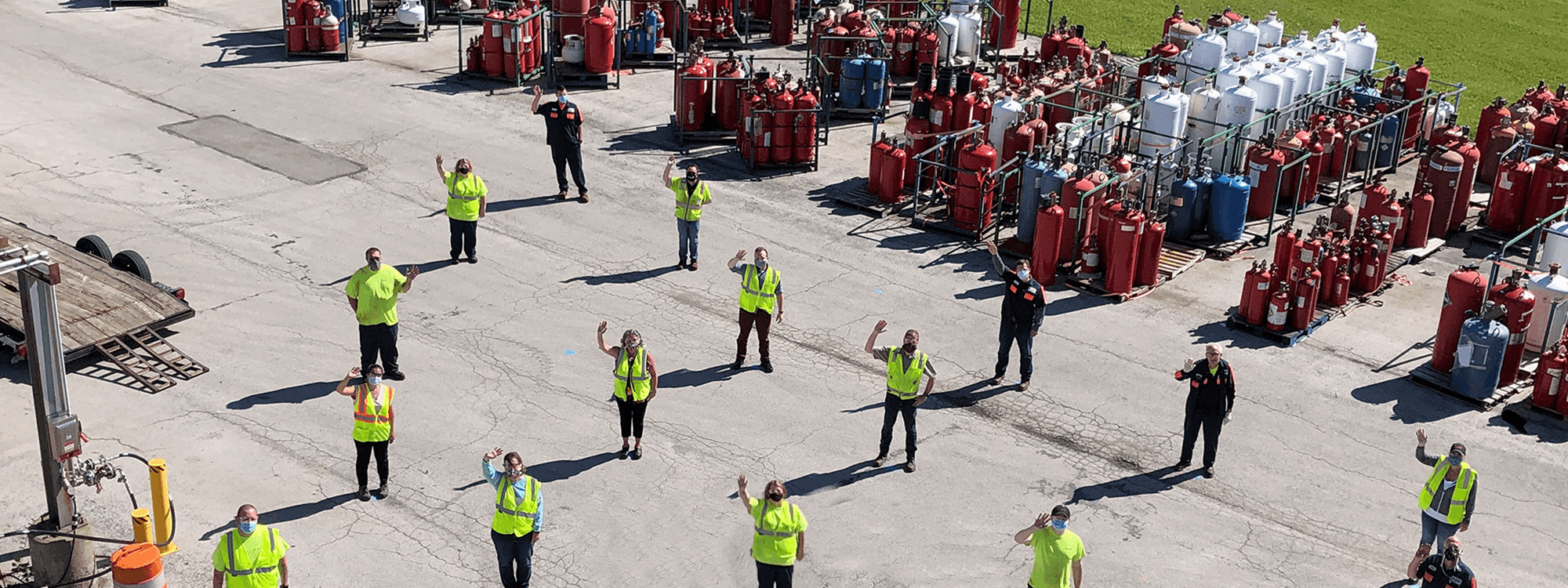 Workers lined up on site waving to the drone taking the photo
