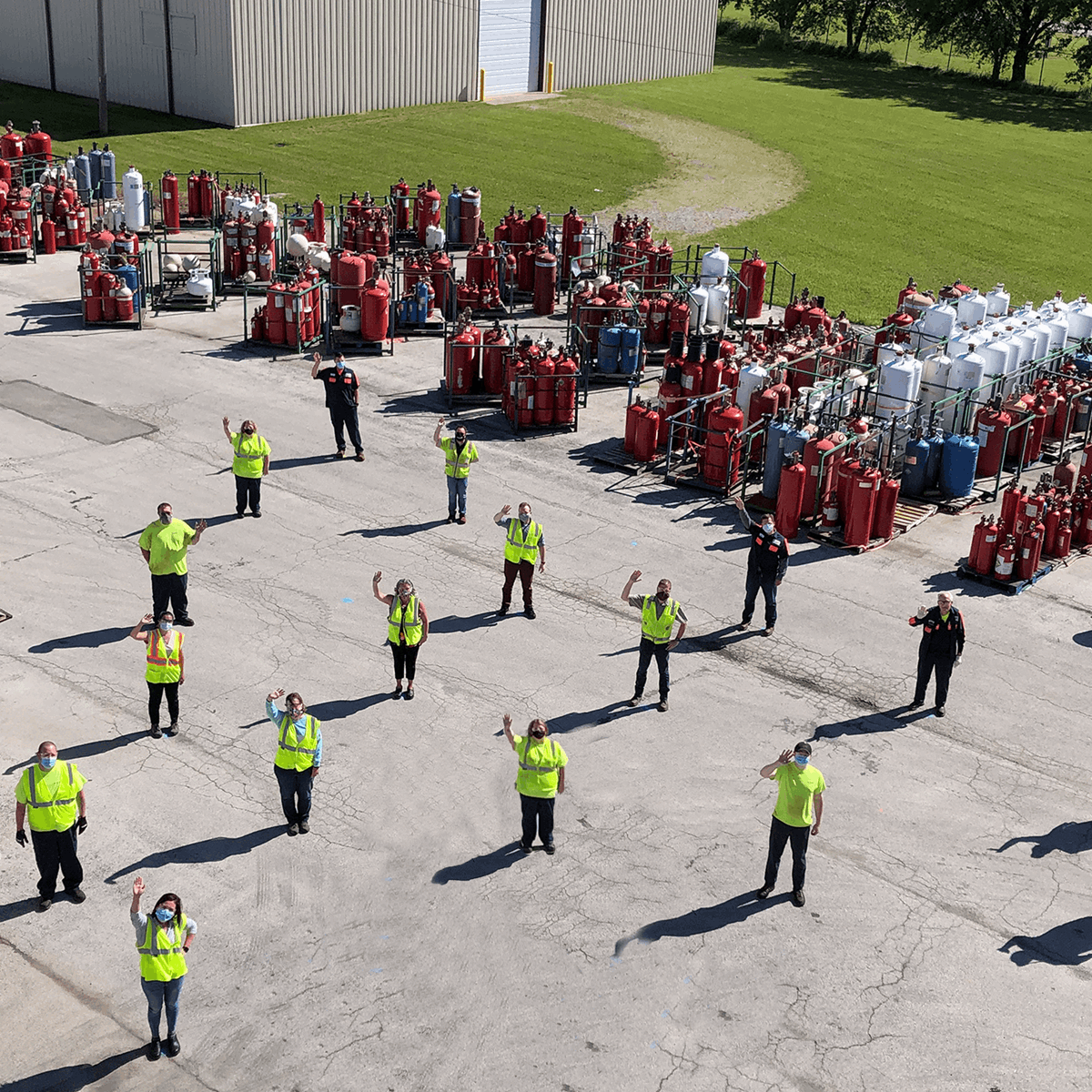 Workers lined up on site waving to the drone taking the photo